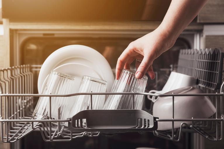 Hand loading dishes in a dishwasher. 