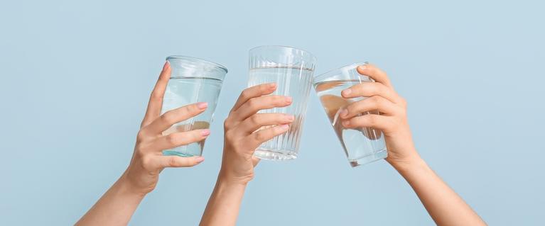 hands raising glasses of water to cheers